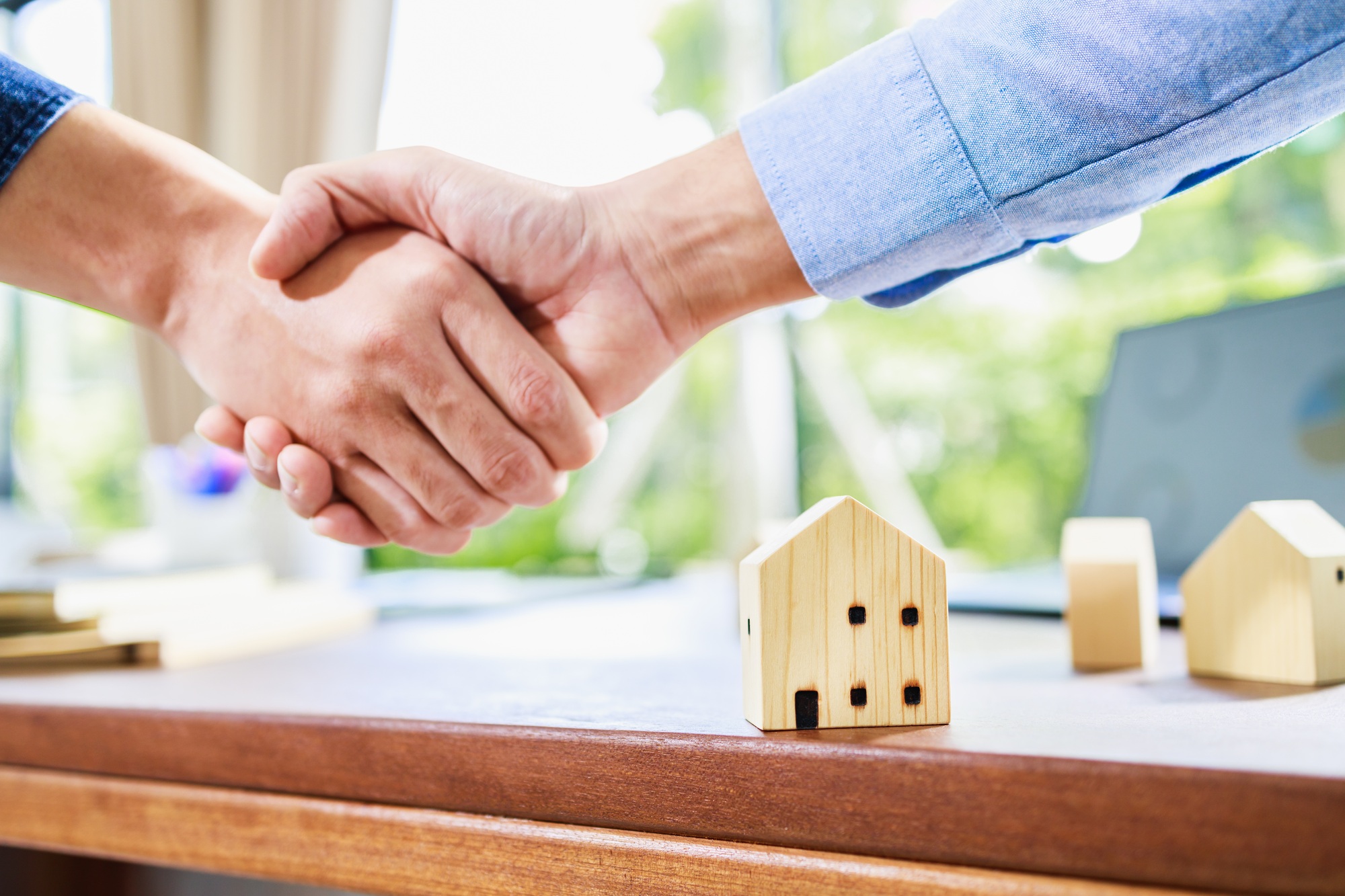 Successful agreement, estate, home buying contract. Focus at home model and handshake in background